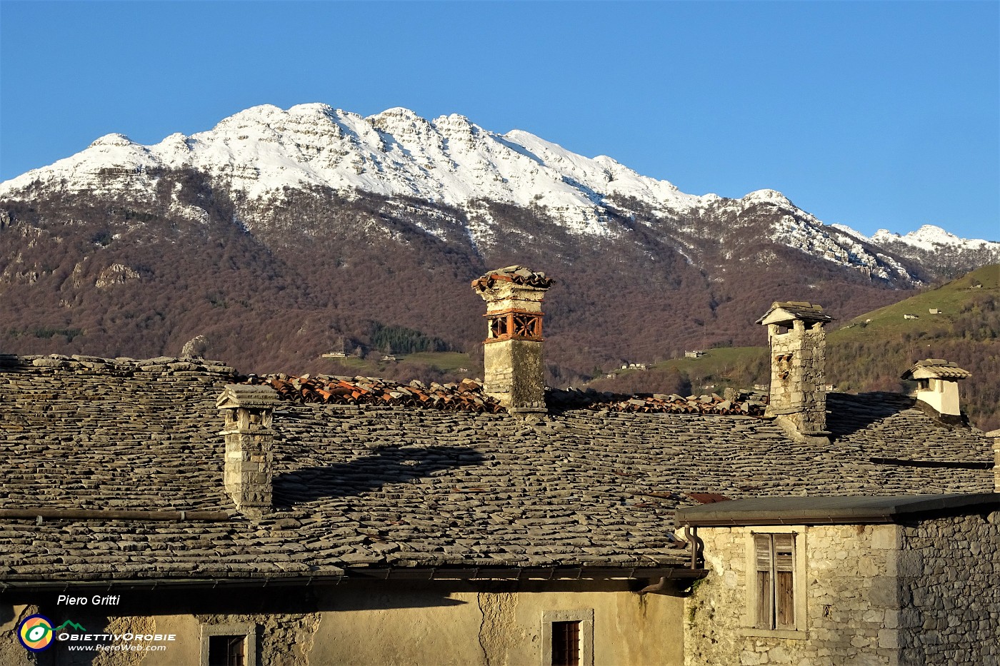 01 Le creste del Resegone, di bianco vestite, sopra i tetti del dell'antico borgo di Arnosto di Fuipiano.JPG